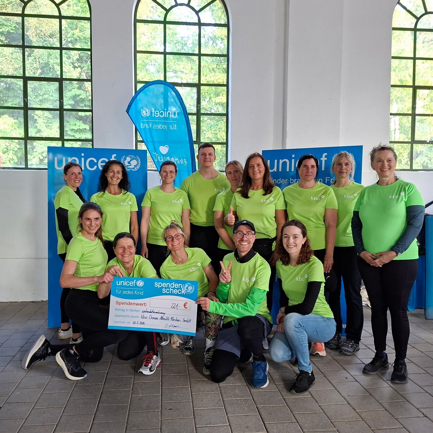 Gruppenbild der kbo-DAK-LäuferInnen vor UNICEF-Logo mit Spendenscheck