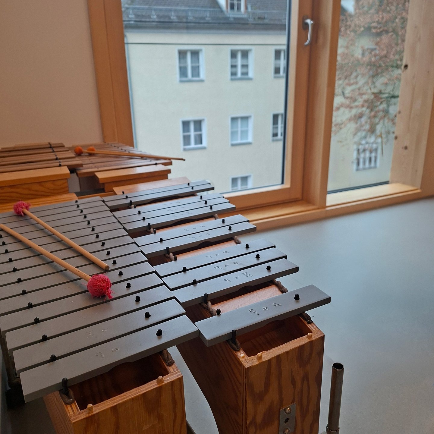 Zwei Metall-Xylophon vor einem Fenster mit Blick auf ein Wohnhaus.